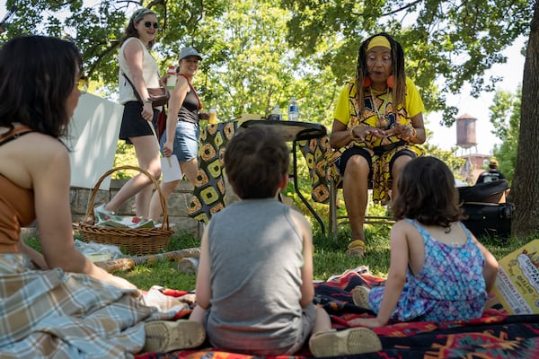 A mom and her two kids listen to a story. Atlanta residents celebrate at the Oakland Cemetary Juneteenth Family Festival. This is the third Juneteenth since becoming a federal holiday in 2021. Saturday, June 15, 2024 (Ben Hendren for the Atlanta Journal-Constitution)