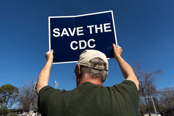 Retired employee Michael Beach holds a sign that says “Save the CDC” during a recent protest against cuts to the Centers for Disease Control and Prevention in front of the CDC Chamblee campus.