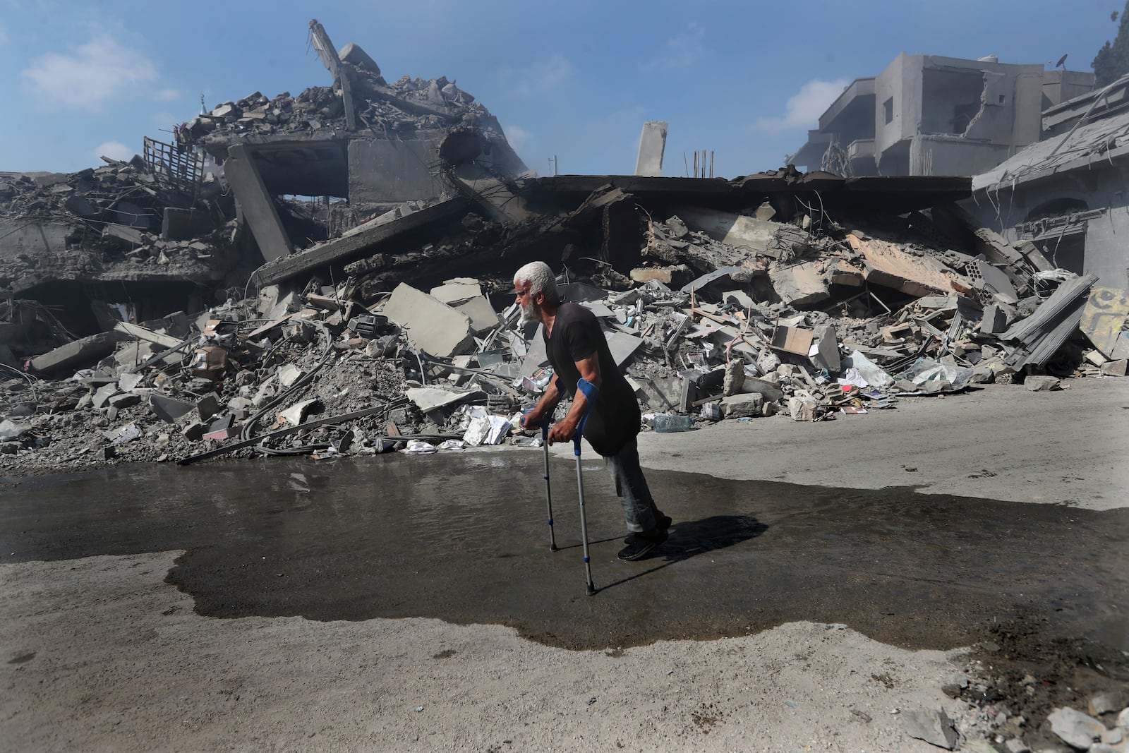 A man walks in front of destroyed buildings on a commercial street that was hit Saturday night by Israeli airstrikes, in Nabatiyeh town, south Lebanon, Sunday, Oct. 13, 2024. (AP Photo/Mohammed Zaatari)