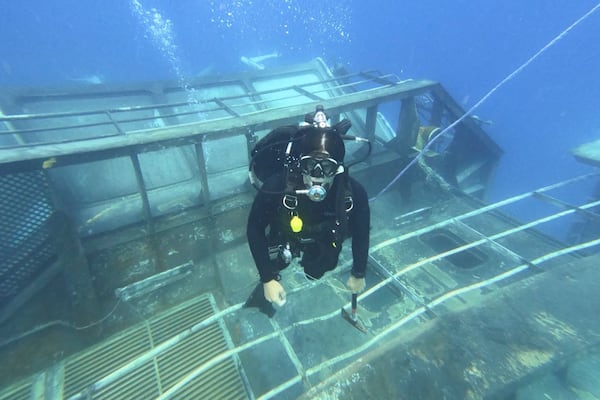 In this Oct 2024 photo provided by the New Zealand Defence Force, a diver survey's the HMNZS Manawanui on the southern coast of Upulo, Samoa, after the Manawanui ran aground and sank on Oct. 6. (New Zealand Defence Force via AP)