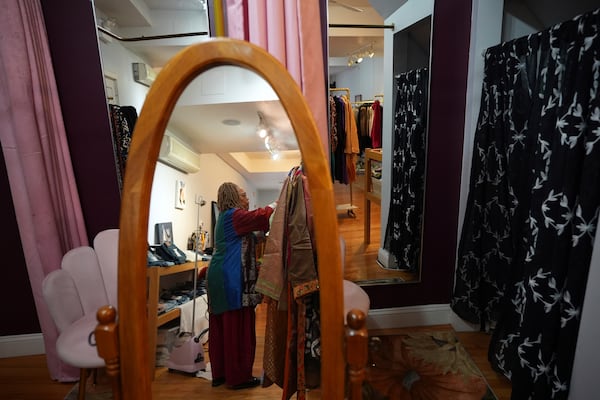 Manager Deborah Averette steams clothing at Between Friends Boutique, Wednesday, Dec. 11, 2024, in Philadelphia. (AP Photo/Matt Slocum)