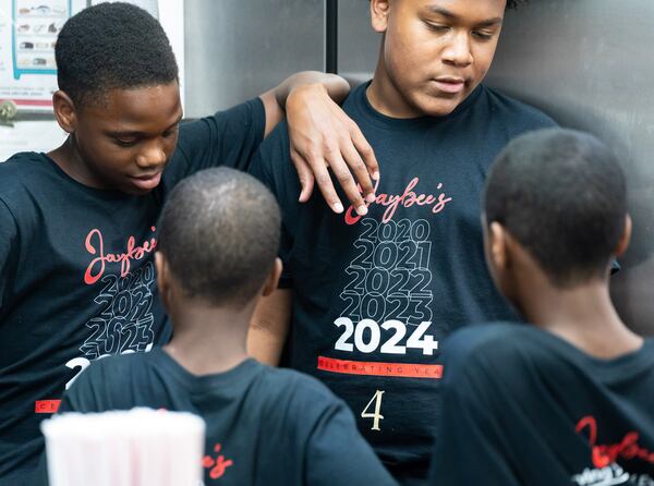 Javonte Harrington, left, leans on his brother Anah-j Reina’s shoulder while working with their family at Jaybee's Tenders in Decatur, GA on Thursday, July 25, 2024. Before they married and founded Jaybee’s Tenders, William and Erika Harrington met because Javonte, 15, and Anah-j, 14, played football together. (Seeger Gray / AJC)