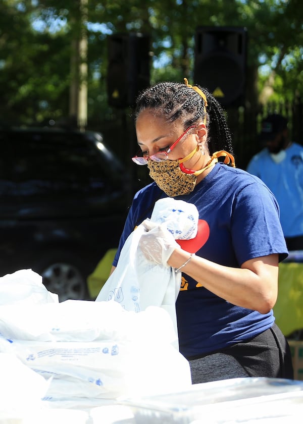 Tammy Tamer bags food during the Grab and Go free food and groceries event on Friday, April 17, 2020, at Allen Hills Apartments in Atlanta. The event to help families during the COVID-19 pandemic was led by the Fulton County district attorney’s office. (Christina Matacotta, for The Atlanta Journal-Constitution)