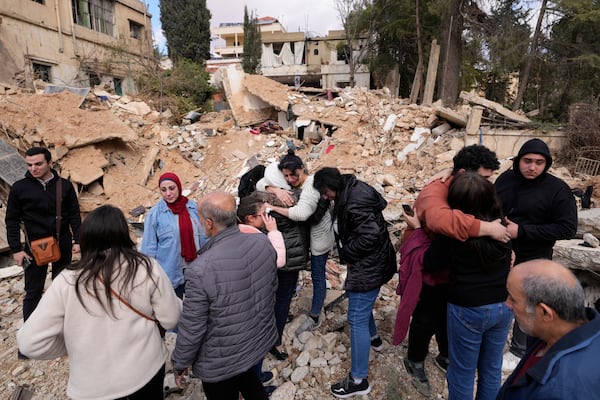 Displaced residents hug as they stand in front of the rubble of their destroyed house in Baalbek, eastern Lebanon, Thursday, Nov. 28, 2024. (AP Photo/Hassan Ammar)