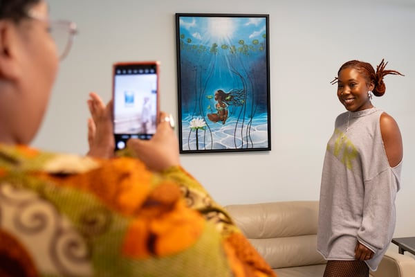 Courtney Ward poses next to her artwork that was hanging in Atlanta’s new Center for Diversion and Services following a ceremony to unveil the center on Monday, Oct. 28, 2024. Ben Gray for the Atlanta Journal-Constitution