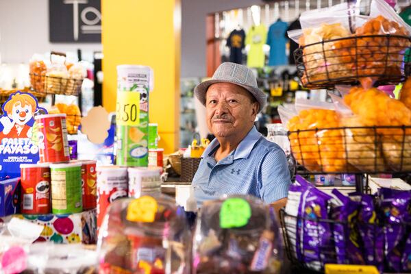 Juan Patiño sits behind the counter of his shop Soy Garapiñados, where he sells snack foods. CHRISTINA MATACOTTA FOR THE ATLANTA JOURNAL-CONSTITUTION.