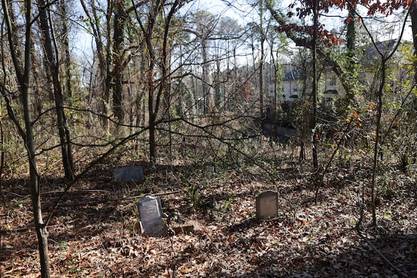 The Bluffs at Lenox townhome development in Buckhead can barely be seen through overgrown vegetation in the adjacent Piney Grove Cemetery. The development's homeowners association denies allegations that it is shirking its responsibility to maintain the cemetery. (Jason Getz / Jason.Getz@ajc.com)