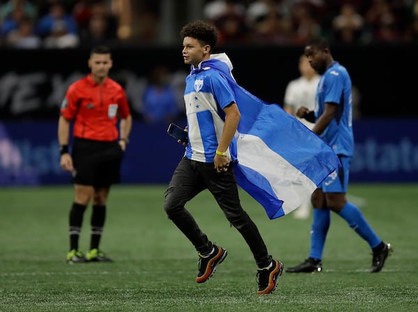 A fan wearing the flag of Honduras runs on the field during the second half of an international friendly soccer match against Mexico, Saturday, June 12, 2021, in Atlanta. (AP Photo/Ben Margot)