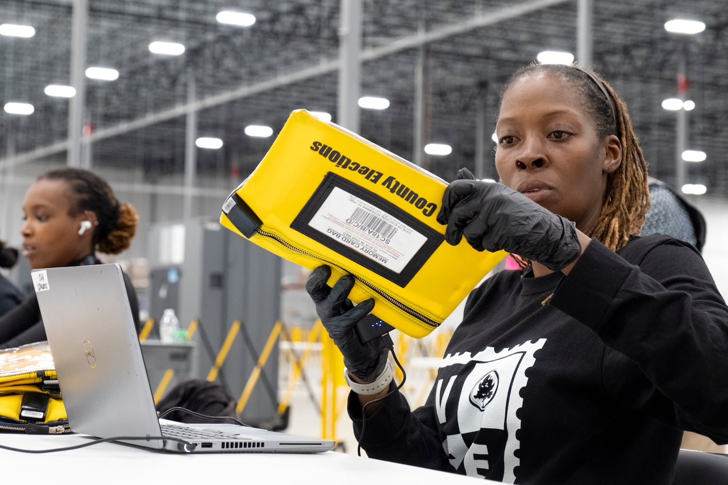 A worker receives some form of the first memory cards to arrive at the Fulton County election hub in Fairburn on Tuesday, Nov. 5, 2024.   Ben Gray for the Atlanta Journal-Constitution