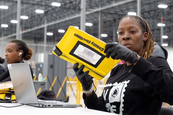 A worker receives some form of the first memory cards to arrive at the Fulton County election hub in Fairburn on Tuesday. Despite more than 32 false bomb threats at polling locations, the county's election operations performed well Tuesday. Ben Gray for The Atlanta Journal-Constitution