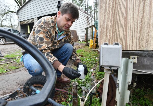 Fletcher Sams, executive director at Altamaha Riverkeeper, collects water samples at John David Johnson's home near Georgia Power's coal-fired power plant in Juliette. Last week, residents filed a lawsuit against Georgia Power asking damages for current and ongoing personal injuries and property damage. (Hyosub Shin / Hyosub.Shin@ajc.com)