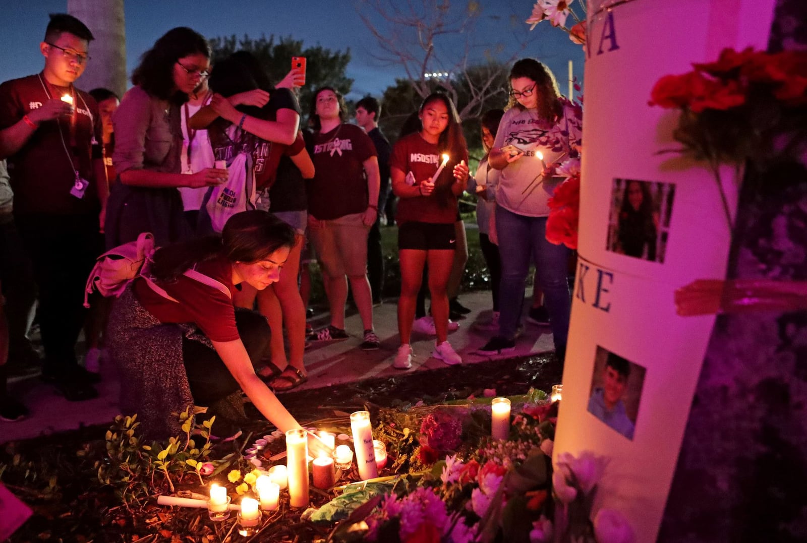 People light candles for a makeshift memorial after an interfaith ceremony in Parkland, Florida, to remember the 17 victims killed in the 2018 Marjory Stoneman Douglas High School shooting.