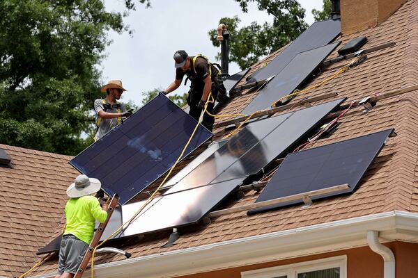 Alternative Energy Southeast employees Lauren Minter, lower left, Aaron Basto, center left, and Russell McCune, right, installs eighteen solar panels to the roof of a resident Tuesday, June 7, 2022, in Ellenwood, Ga. (Jason Getz / Jason.Getz@ajc.com)