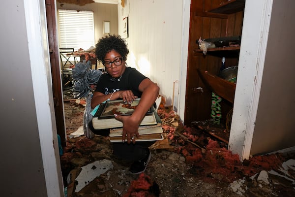 April Willars collects items such as old family photographs in her damaged home, Thursday, Jan. 30, 2025, in Conyers, Ga. Chris and April Willars were on the property to salvage any items they could. They were also impacted by the Biolab fire and a tornado in the past year. (Jason Getz / AJC)