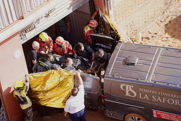 Members of the Spanish Guardia Civil carry the body of a person who died during floods in Valencia, Spain, Thursday, Oct. 31, 2024. (AP Photo/Alberto Saiz)