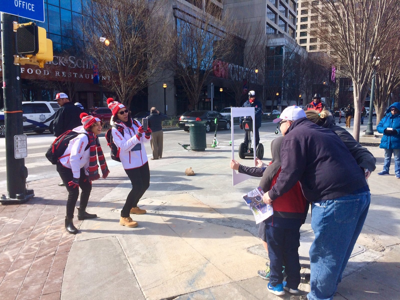 Super Bowl volunteers Lindsey Henry (left) and Lisa Pruitt frame a family of visitors for a street photo shoot in downtown Atlanta. 