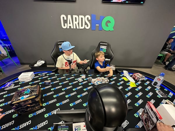 At the CardsHQ YouTube ripping station, 5-year-old Braxton Hallewell (right) of Cumming shows off some of his NBA G League cards he just opened. To his left is Grayson Alvarez. RODNEY HO/rho@ajc.com