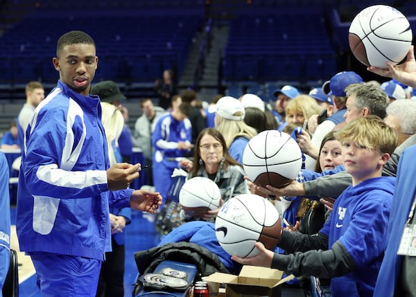 Kentucky's Lamont Butler, left, gives autographs to fans after an NCAA college basketball game against Louisville in Lexington, Ky., Saturday, Dec. 14, 2024. (AP Photo/James Crisp)