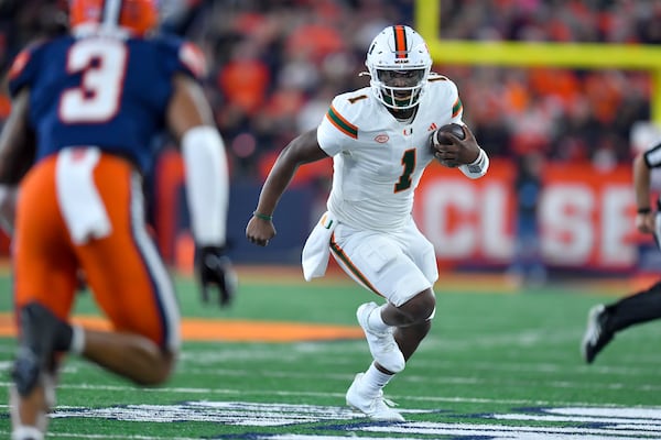 Miami quarterback Cam Ward (1) runs with the ball during the first half of an NCAA football game against Syracuse on Saturday, Nov. 30, 2024 in Syracuse, N.Y. (AP Photo/Adrian Kraus)