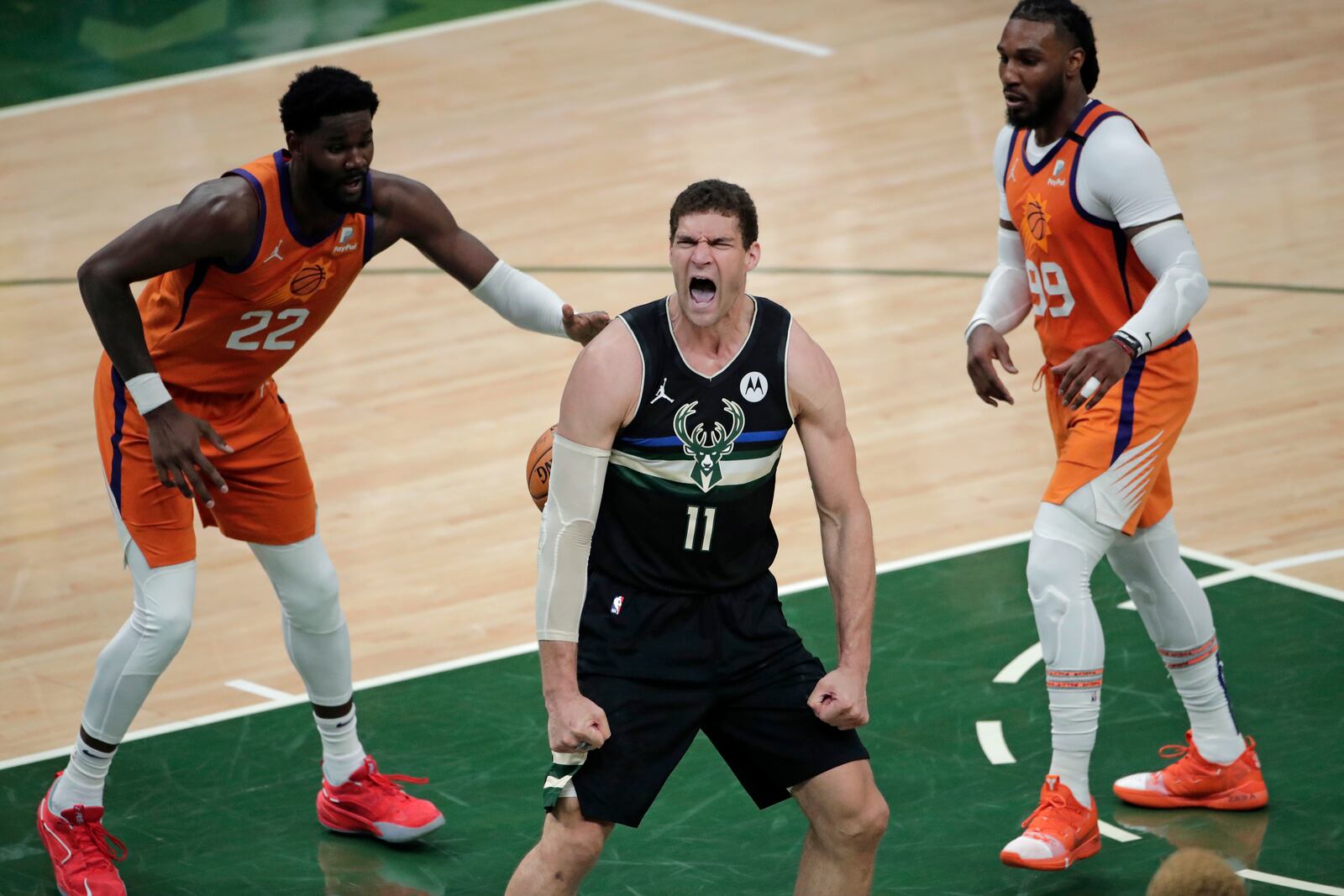 Milwaukee Bucks center Brook Lopez (11) reacts after a slam dunk in front of Phoenix Suns center Deandre Ayton (22) and forward Jae Crowder (99) during the second half of Game 6 of basketball's NBA Finals Tuesday, July 20, 2021, in Milwaukee. (AP Photo/Aaron Gash)