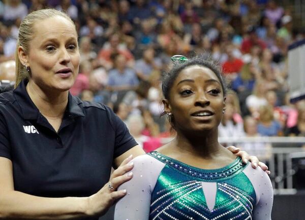 In this 2019 photo, Simone Biles walks with her coach Cecile Canqueteau-Landi after competing in the beam during the senior women's competition at the U.S. Gymnastics Championships in Kansas City, Mo. (AP Photo/Charlie Riedel)