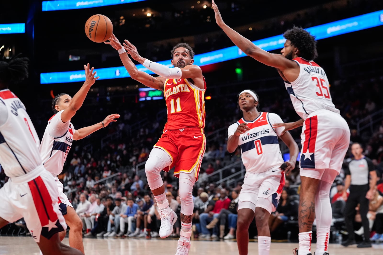 Atlanta Hawks guard Trae Young (11) passes the ball as he goes past Washington Wizards defenders Kyshawn George (18), Bilal Coulibaly (0), and Marvin Bagley III (35) during the first half of an NBA basketball game Monday, Oct. 28, 2024, in Atlanta. (AP Photo/ John Bazemore)