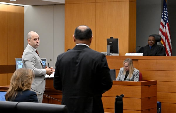 Attorney Sachin Varghese (foreground) representing the Democrat Party, speaks as Robert Thomas (left) representing the State Election Board looks on as Fulton County Superior Court Judge Thomas Cox presides over cases against State Election Board rules. (Hyosub Shin / AJC)