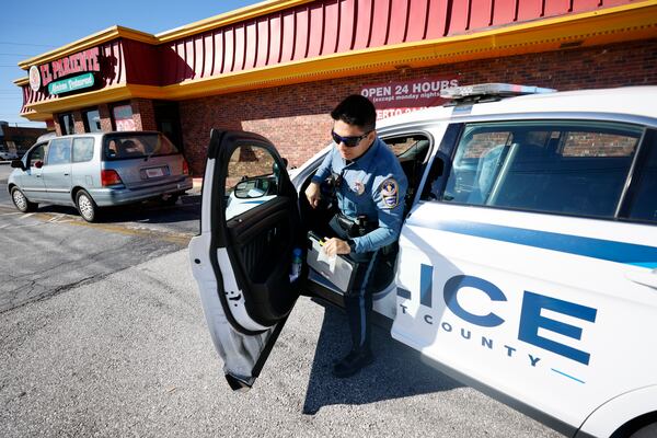 Sr. Officer Daniel Arrata exits his patrol vehicle with a ticket he just wrote to someone because he was driving with a cellphone. The proposed Gwinnett budget includes language lessons for employees to help with the language barriers between officers and residents.
 Miguel Martinez / miguel.martinezjimenez@ajc.com