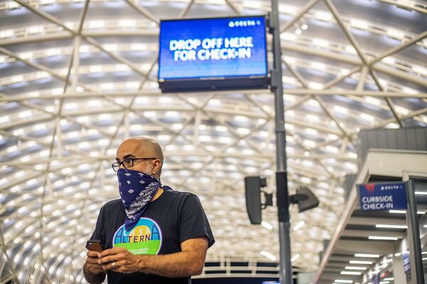 Casa Alterna co-founder Anton Flores-Maisonet checks his phone while waiting for a drop-off of immigrants from the Stewart Detention Center at the curbside lanes of the domestic terminal at Atlanta's Hartsfield-Jackson International Airport, Thursday, Aug. 19, 2021. Volunteers with Casa Alterna, which was started during the COVID-19 pandemic, are stationed at the airport to assist immigrants and asylum seekers who are released from immigration detention in Georgia. Flores-Maisonet often receives messages that will alert him when a van carrying immigrants leaves the center and is headed to the airport.  (Alyssa Pointer/Atlanta Journal Constitution)