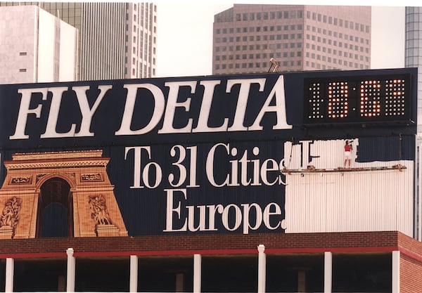 Sign painter Dianna Snell puts the finishing touches on the downtown Delta sign that greets over more than 300,000 motorists every day. (AJC 1990 file photo)