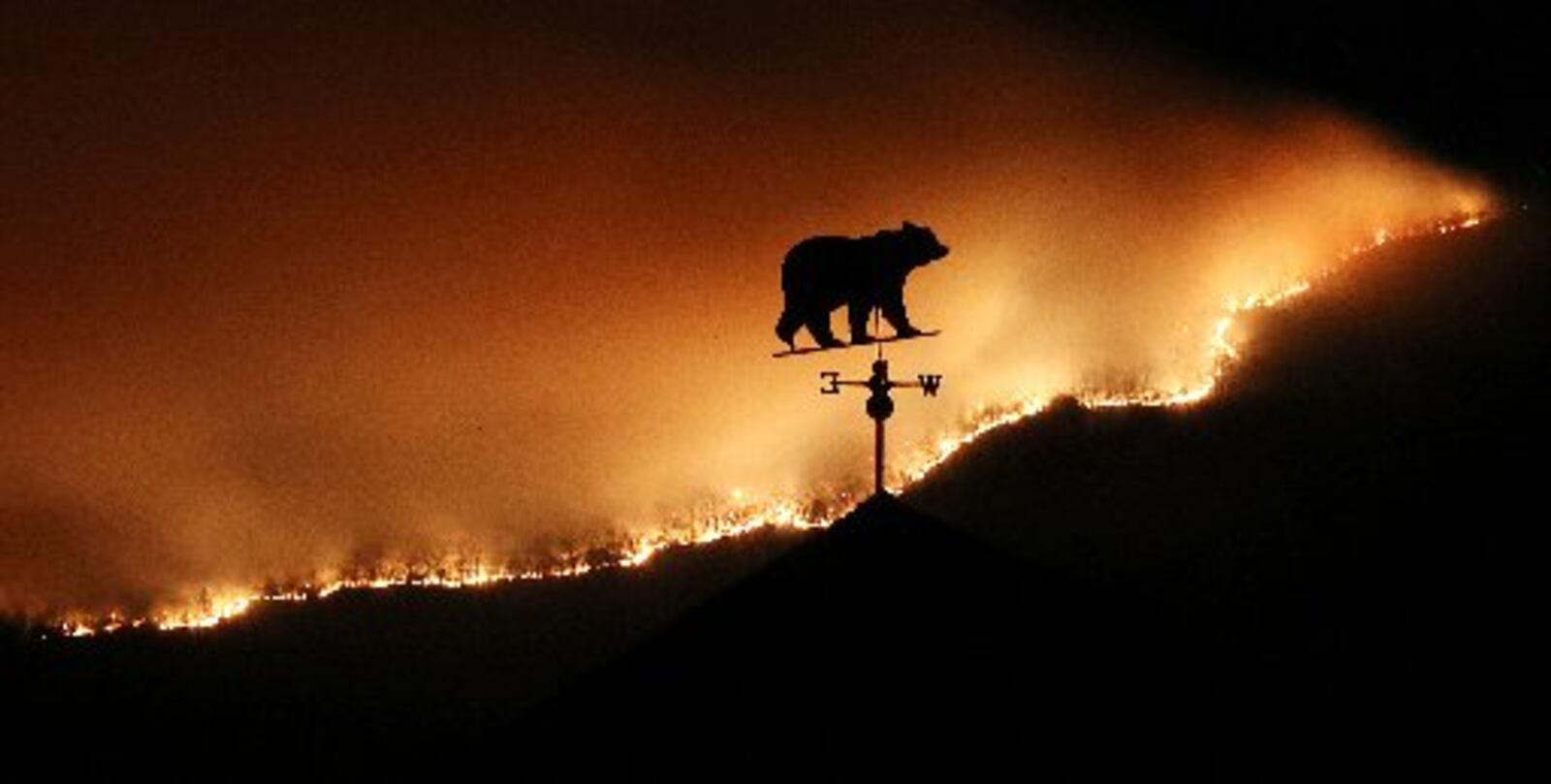 At first glance, the weather vane on top of a barn appears to be a bear fleeing the Rock Mountain fire as it burns near Bettys Creek Road. CURTIS COMPTON / CCOMPTON@AJC.COM