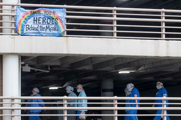 In this photo from April, early in the pandemic, health workers walk toward the entrance of Floyd Medical Center in Rome, Georgia.  The hospital in northwest Georgia saw one of the state's first COVID-19 surges. (PHOTO by ALYSSA POINTER / Alyssa.Pointer@AJC.com)