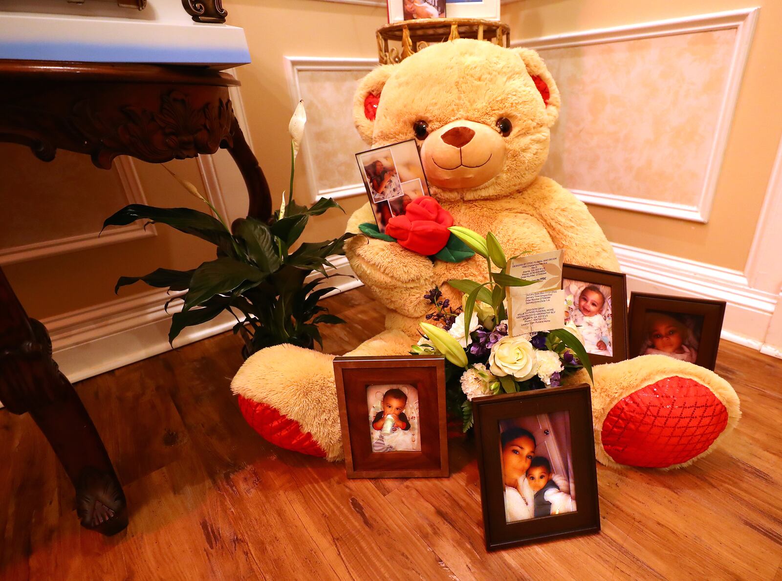 A teddy bear, flowers and photographs sit in the room next to the coffin during the public visitation for 6-month-old Grayson Fleming-Gray.