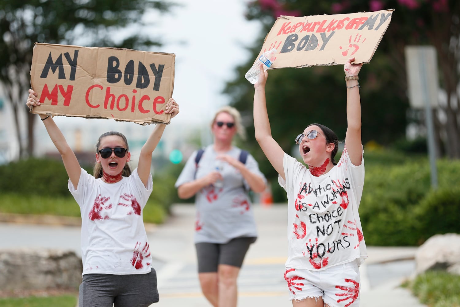 Erika Schulte and Ansley Banks covered their shirts with signs to protest the  U.S. Supreme Court's overturning of Roe v Wade. Sunday, June 26, 2022. Miguel Martinez /miguel.martinezjimenez@ajc.com