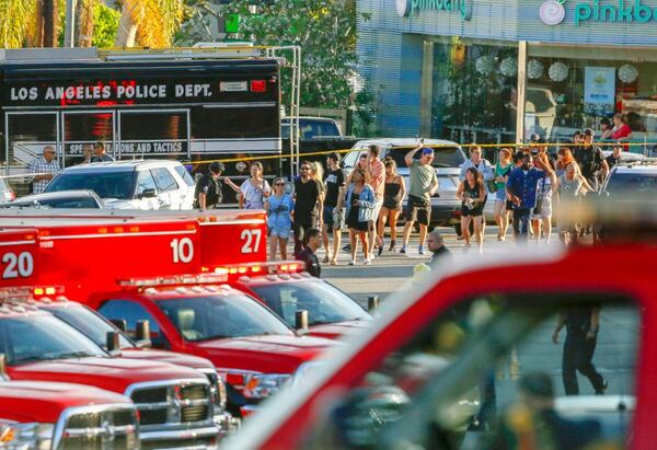 Los Angeles Police SWAT officers escort a group of people who were held for their safety by police across businesses surrounding a Trader Joe's supermarket, after a gunman held dozens of people hostage inside the store before surrendering to police in Los Angeles Saturday, July 21, 2018.  (AP Photo/Damian Dovarganes)