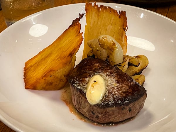 The wood-fired filet mignon at Bocado is topped with bone marrow butter. Grilled cipollini onions and crispy potato pavé are served alongside. (Henri Hollis/AJC)