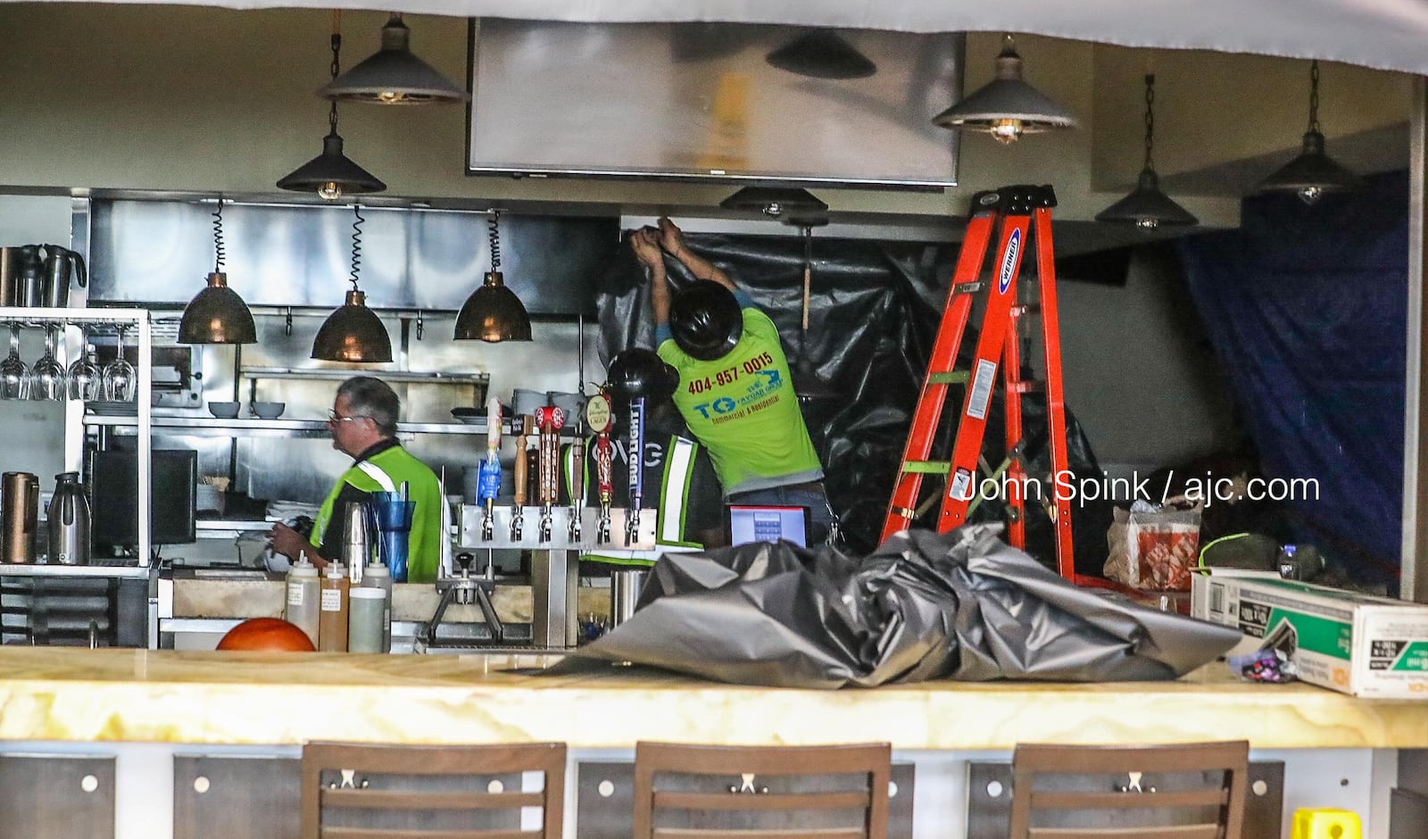 Workers  attach black plastic sheeting to the walls of Cat Cora's Kitchen, which is closed while a repairs are underway.