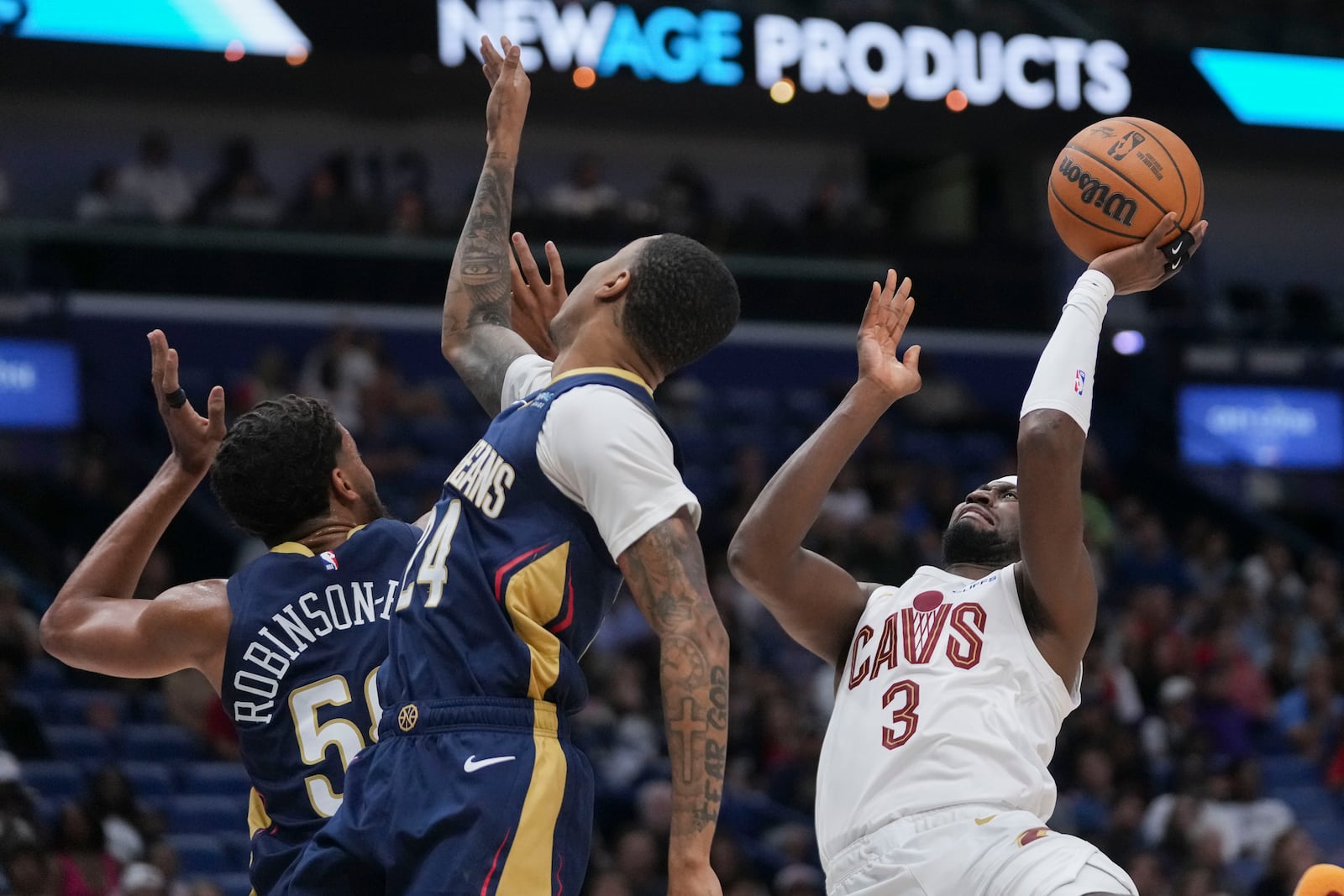 Cleveland Cavaliers guard Caris LeVert (3) shoots against New Orleans Pelicans guard Jordan Hawkins (24) and forward Jeremiah Robinson-Earl (50) in the first half of an NBA basketball game in New Orleans, Wednesday, Nov. 6, 2024. (AP Photo/Gerald Herbert)