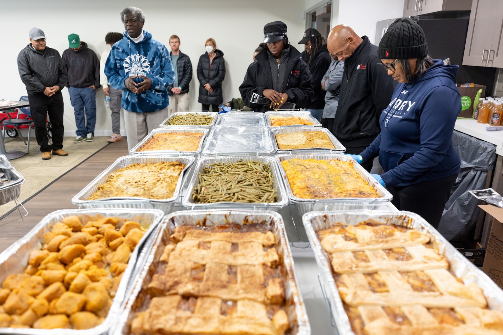 Actor Afemo Omilami says a prayer over the Thanksgiving day meals delivered to the James Allen Jr Place Apartments in Atlanta on Thursday, Nov. 23, 2023. Through a vast volunteer network, Hosea Helps prepared and delivered 1200 hot meals Thursday to people around Atlanta.  (Steve Schaefer/steve.schaefer@ajc.com)