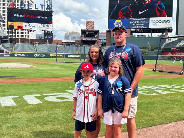 Make-A-Wish child Baylor Skelton, age 8, (bottom left) and his mother, Shiloh (top left), father, Nathan (top right) and big sister, Brinlee (bottom right) standing on the field at Truist Park, July 23, 2024. Baylor was there to meet Braves legend Chipper Jones, his idol. (Photo by Daniela Ramirez/The Atlanta Journal-Constitution)