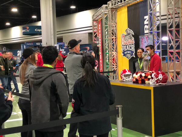 Fans get their pictures taken with the trophy from the Rose Bowl, the game that sent Georgia to the college football national championship being played Monday night at Mercedes-Benz Stadium in Atlanta. 