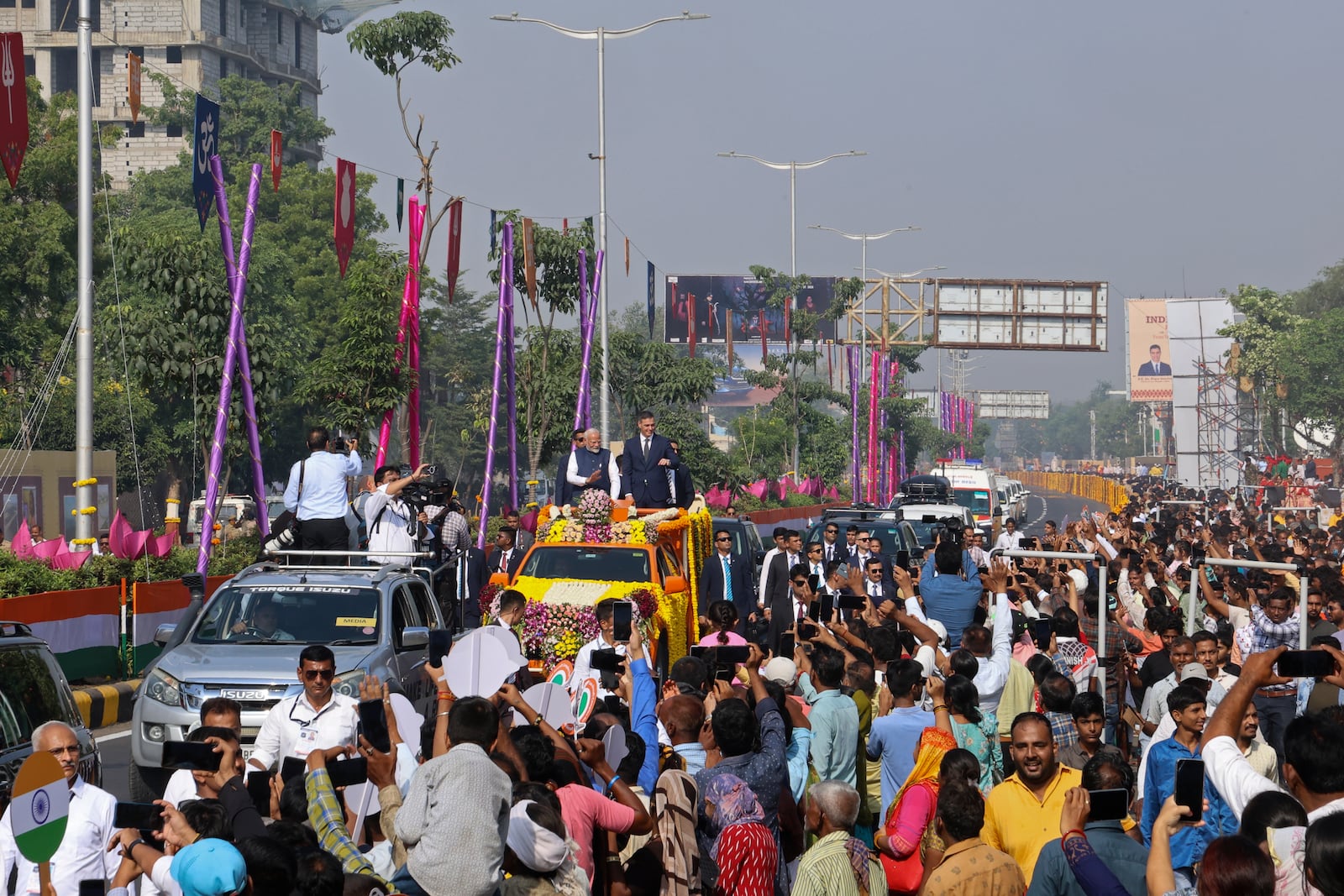 Indian Prime Minister Narendra Modi, center left, and his Spanish counterpart Pedro Sanchez, center right, wave to greet people from a vehicle in Vadodara, India, Monday, Oct. 28, 2024. (AP Photo)