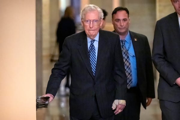 Senate Minority Leader Mitch McConnell of Ky., left, wears a bandage on his face and wrist as he walks to cast a vote on the Senate floor after falling during a luncheon on Capitol Hill, Tuesday, Dec. 10, 2024, in Washington. (AP Photo/Mark Schiefelbein)