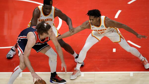 Clint Capela and De'Andre Hunter guard Wizards' Robin Lopez in the second half of an NBA basketball game Monday, May 10, 2021, in Atlanta.