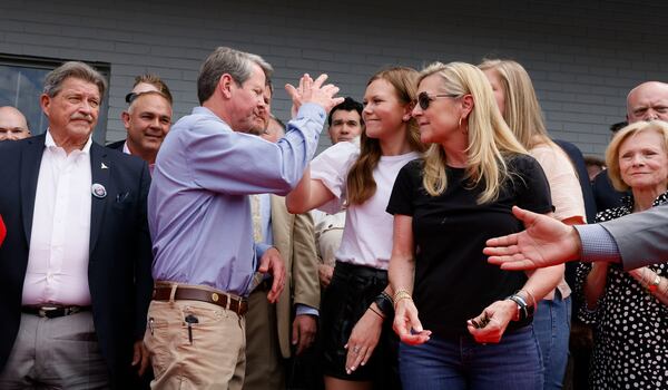 Gov. Brian Kemp high-fives with his family after he signed a bill in April to allow Georgians to carry firearms without first getting a permit. Kemp has focused attention on conservative causes, such as anti-abortion measures and expansions of gun rights to maintain appeal with Donald Trump's followers. (Bob Andres / robert.andres@ajc.com)