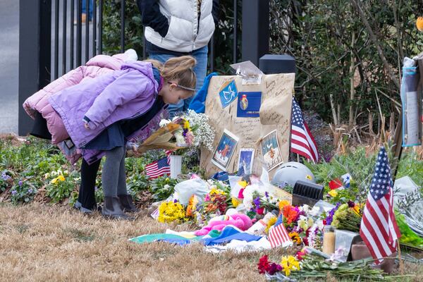 Girls put flowers at a memorial at the Carter Center in Atlanta on Sunday, January 5, 2025. Former president Jimmy Carter, who died at 100, is lying in repose at the center. (Arvin Temkar / AJC)