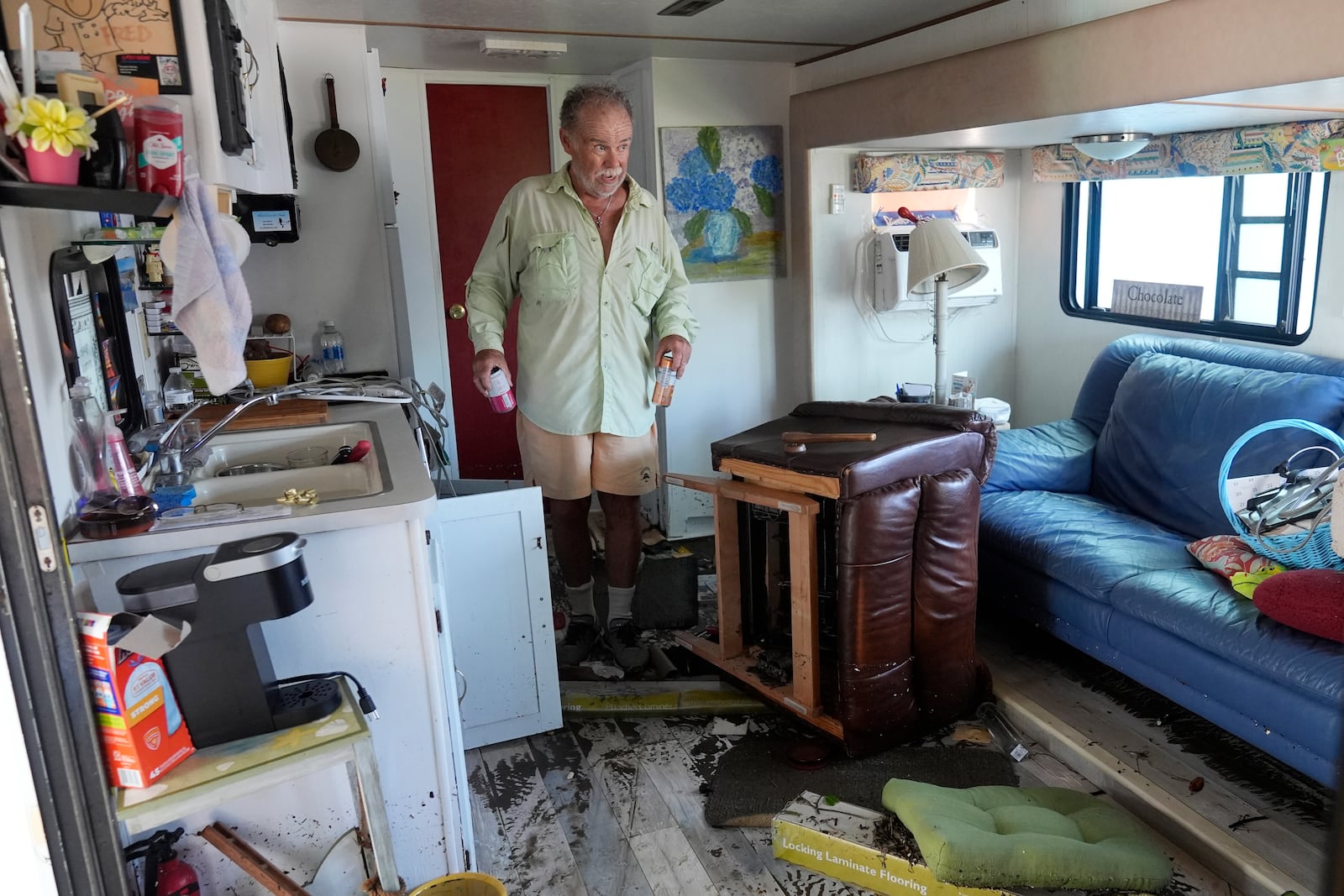 Fred Hill gets a few drinks from his destroyed home after it was hit by a tornado and flooding caused by Hurricane Milton, Thursday, Oct. 10, 2024, in Matlacha, Fla. (AP Photo/Marta Lavandier)