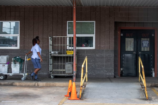 A U.S. Postal Service worker takes a cart inside the post office at 822 Ralph McGill Boulevard NE in Atlanta on Friday. (ALYSSA POINTER / ALYSSA.POINTER@AJC.COM)