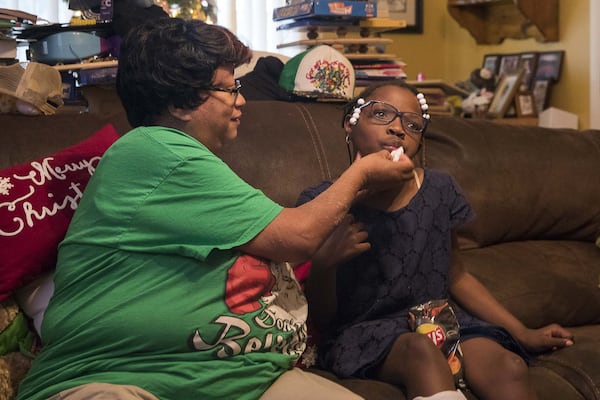 Patricia Moses, 52, wipes crumbs off the face of her adopted daughter Ariah at their residence in Decatur. Patricia and her twin sister Priscilla have been foster parents for more than 20 children. Their first foster kids were their cousin’s children. They have since adopted three children. 