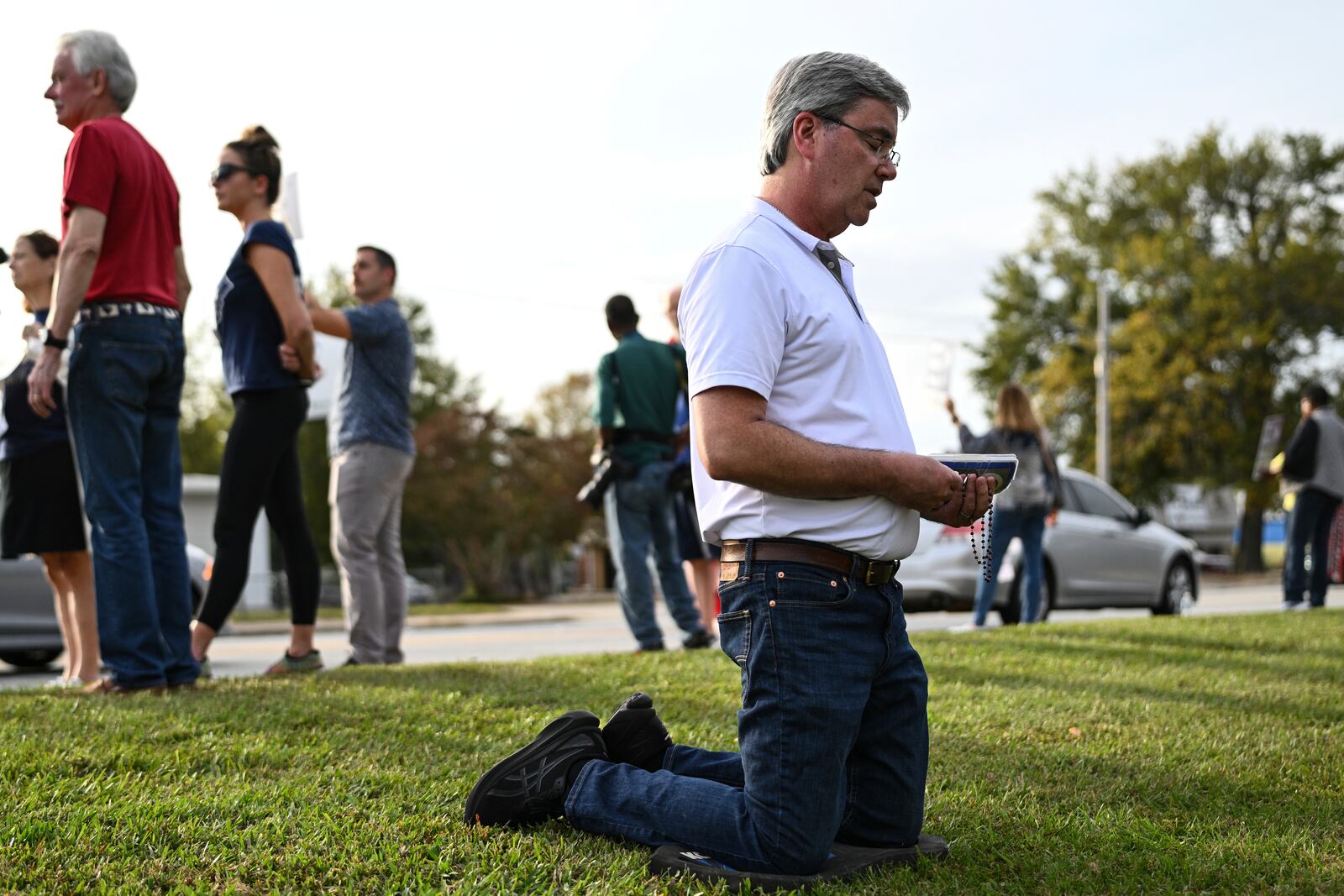 A protestor kneels to pray prior to the scheduled execution of Richard Moore, Friday, Nov. 1, 2024, outside of Broad River Correctional Institution in Columbia , S.C. (AP Photo/Matt Kelley)